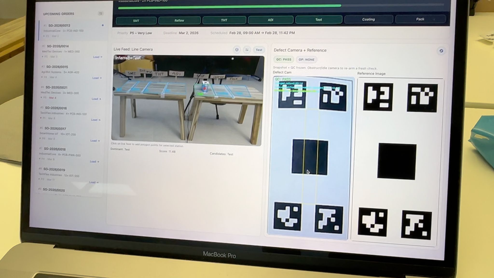 A laptop showing the dashboard built during the hackathon: a queue of production orders, a live line camera and a defect camera with its reference image.